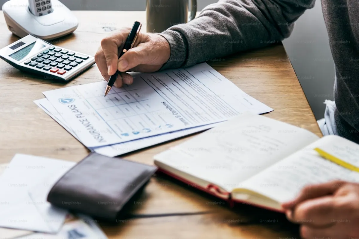 Person reviewing finances on a phone with a laptop nearby