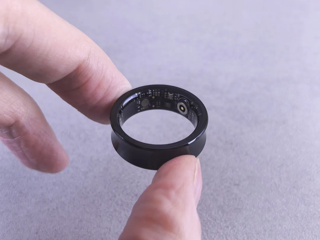 Fingers hold a black smart ring with circuits visible. | Photo by Andrey Matveev on Unsplash