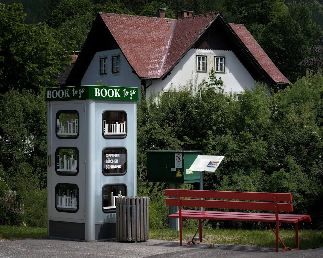 A book to go kiosk sits near a red bench. | Photo by Fajar Al Hadi on Unsplash