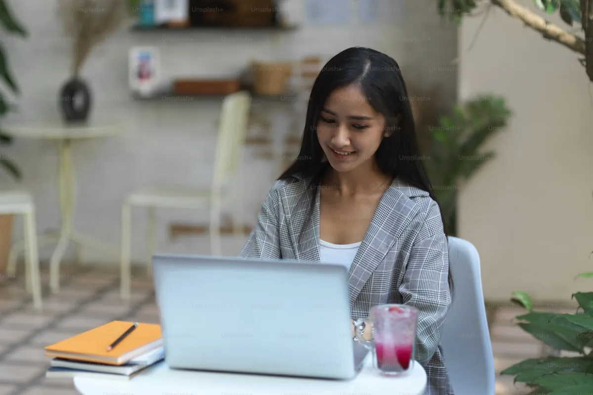 Person working on a laptop at a coffee shop with notes and planner