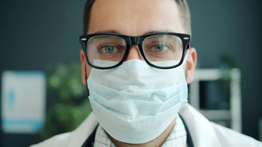 Doctor wearing a mask and glasses looking directly. | Photo by Vitaly Gariev on Unsplash