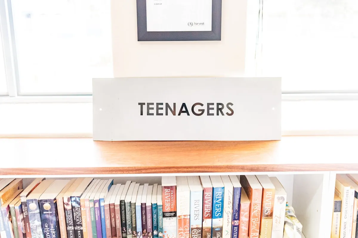 Teenager reading a book at a desk in a library | Photo by Unsplash