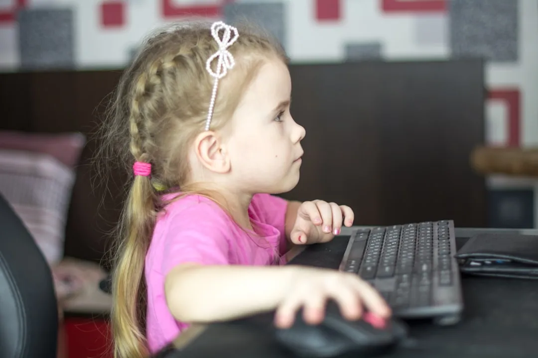 a little girl sitting in front of a computer keyboard | Photo by Bermix Studio on Unsplash