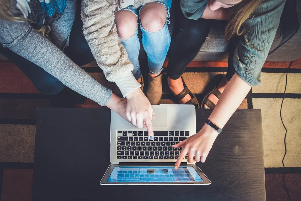Person helping another person use a laptop computer | Photo by Unsplash